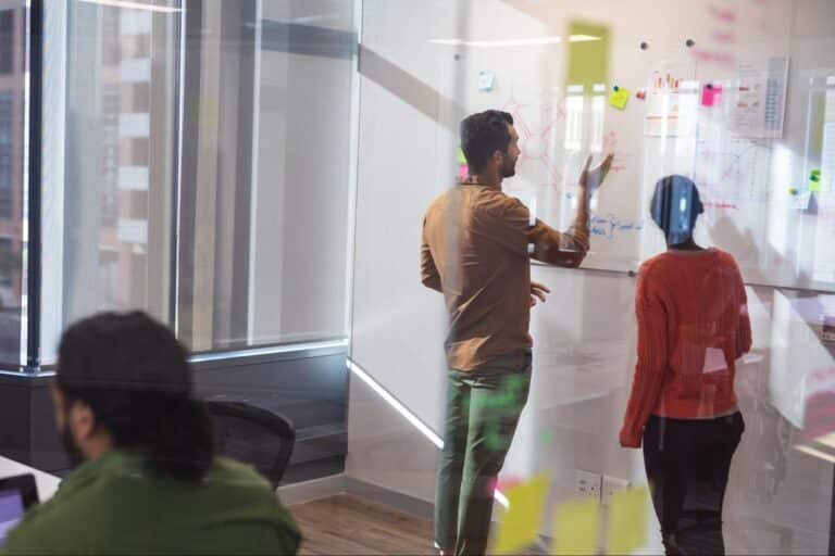Team brainstorming in a modern office, utilizing collaborative wall space for creative ideas.