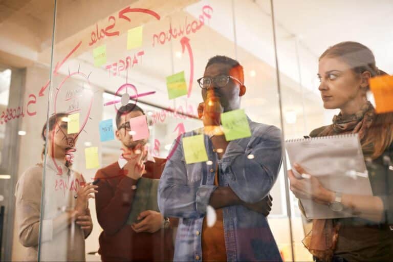 Creative team brainstorming session with notes and ideas on a glass wall.