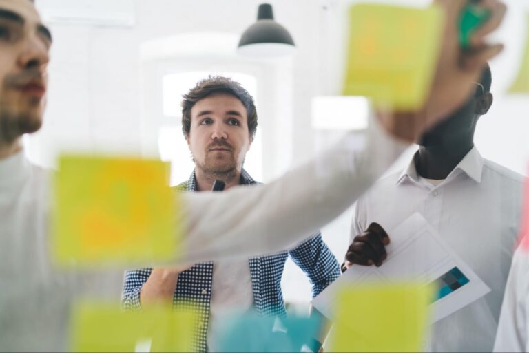 Team members brainstorming with colorful sticky notes in a bright office setting.