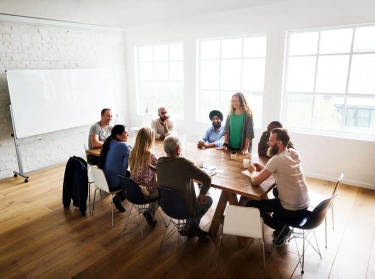 Team collaboration in a bright meeting room with large windows.